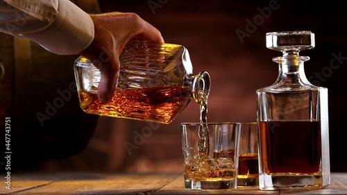 Freeze motion of man hand pouring whisky shot