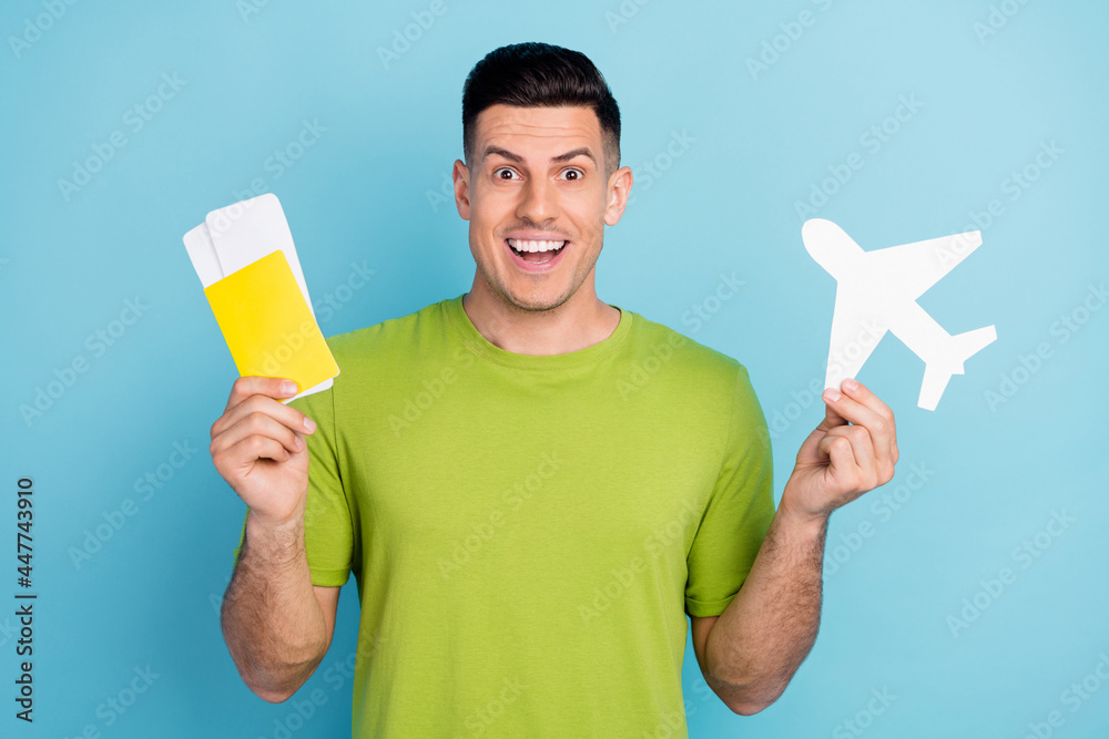 Photo of young happy amazed man hold hands plane paper tickets vacation isolated on blue color background Photo of young happy amazed man hold hands plane paper tickets vacation isolated on blue color background
