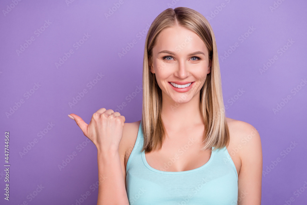 Photo of sweet blond young lady point empty space wear blue top isolated on violet color background Photo of sweet blond young lady point empty space wear blue top isolated on violet color background