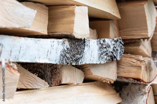 stacked woodpile of birch firewood in nature in the village on a bright summer day. Close-up