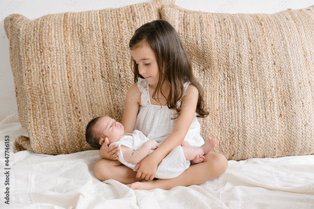 © ADDICTIVE STOCK - Smiling girl sitting with newborn on bed