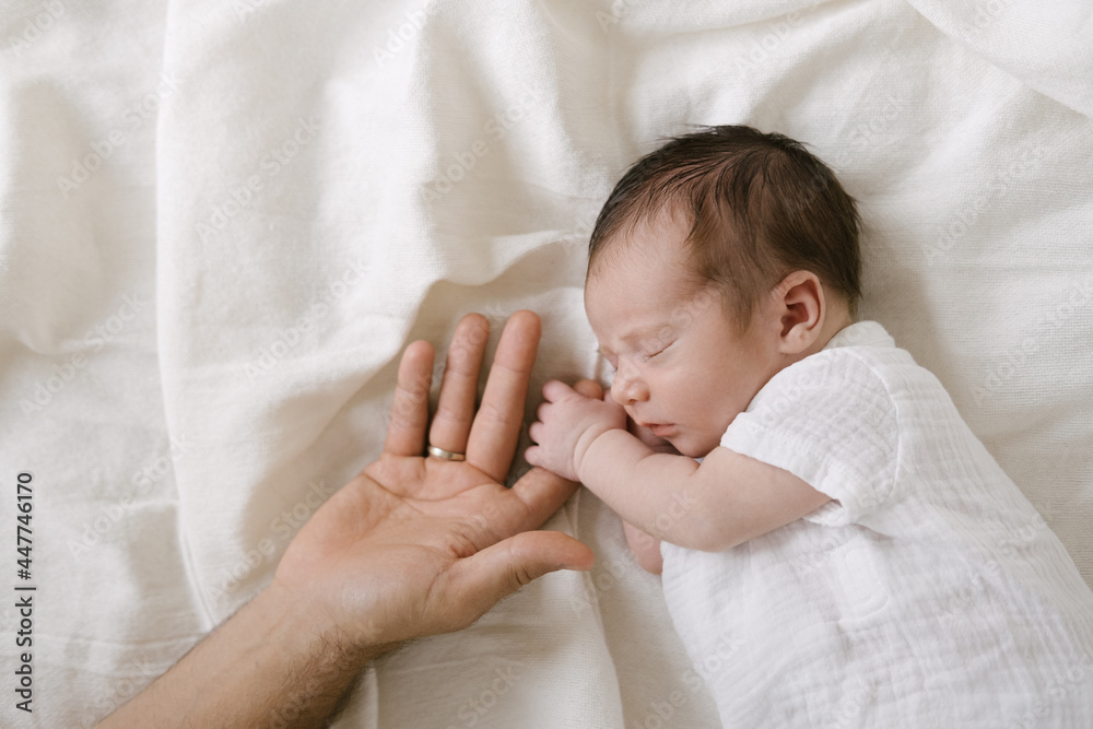 © ADDICTIVE STOCK - Sleeping newborn holding finger of crop parent