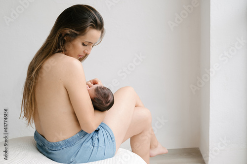 Mother breastfeeding baby in room at home