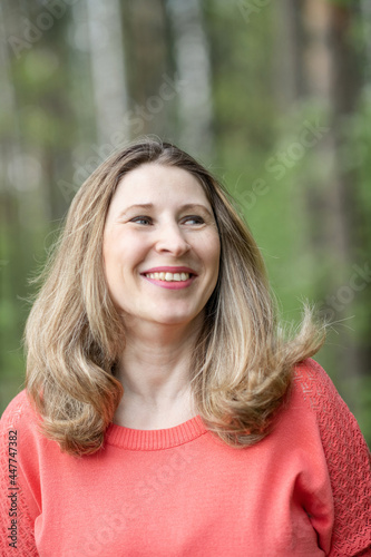 Portrait of a cheerful young blonde girl in the park.