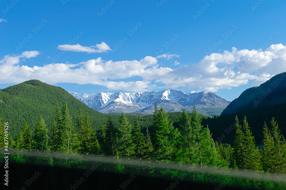 Altai mountains range with snow-covered peaks and blue sky. Travelling by car.