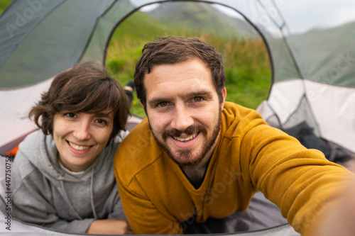 Obraz na płótnie Happy couple inside a tent taking a selfie and enjoying a romantic vacation camping in Scotland w salonie