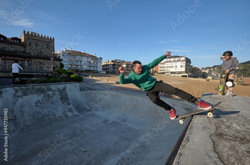 Skaters showing tricks on ramp in skate park photo