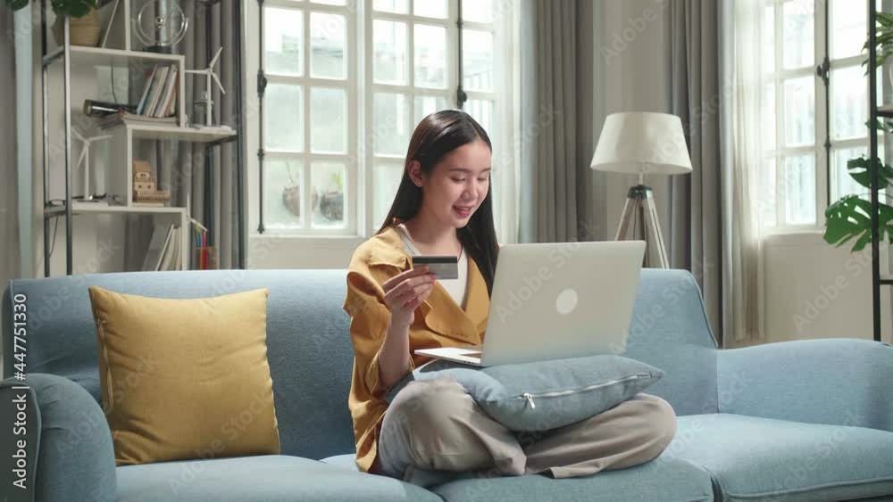 Asian Woman Sitting On Couch In Living Room Holding Credit Card And Using Laptop Computer Shopping Online
Asian Woman Sitting On Couch In Living Room Holding Credit Card And Using Laptop Computer Shopping Online