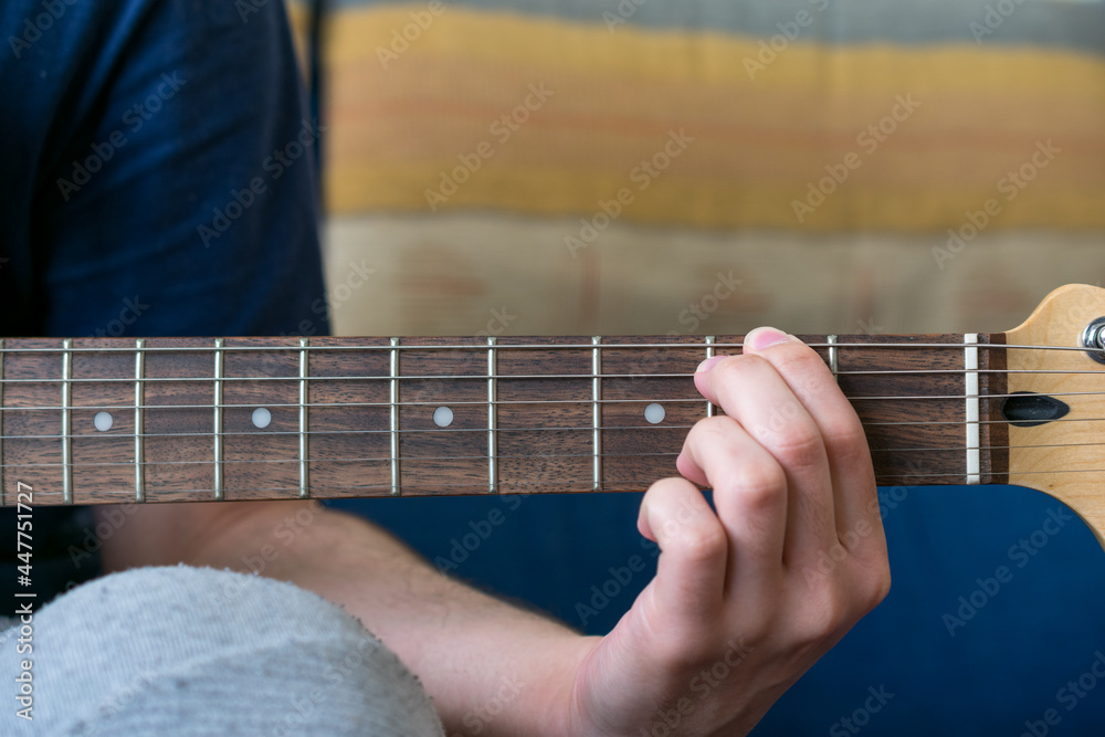 Front-view of an unrecognizable man playing an electric guitar, with his hand on the neck of the guitar. Front-view of an unrecognizable man playing an electric guitar, with his hand on the neck of the guitar.