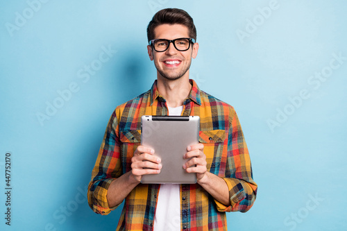 Portrait of attractive cheerful guy geek holding in hands using device app 5g isolated over bright blue color background photo