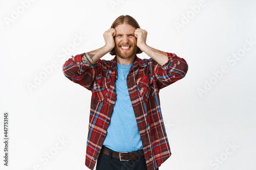 Frustrated and distressed blond bearded man squeeze teeth, frowning and looking in pain, have trouble, painful headache, standing over white background