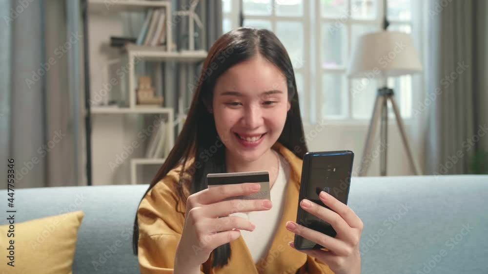 Asian Woman Sitting On Couch In Living Room Holding Credit Card And Using Smartphone Shopping Online
Asian Woman Sitting On Couch In Living Room Holding Credit Card And Using Smartphone Shopping Online