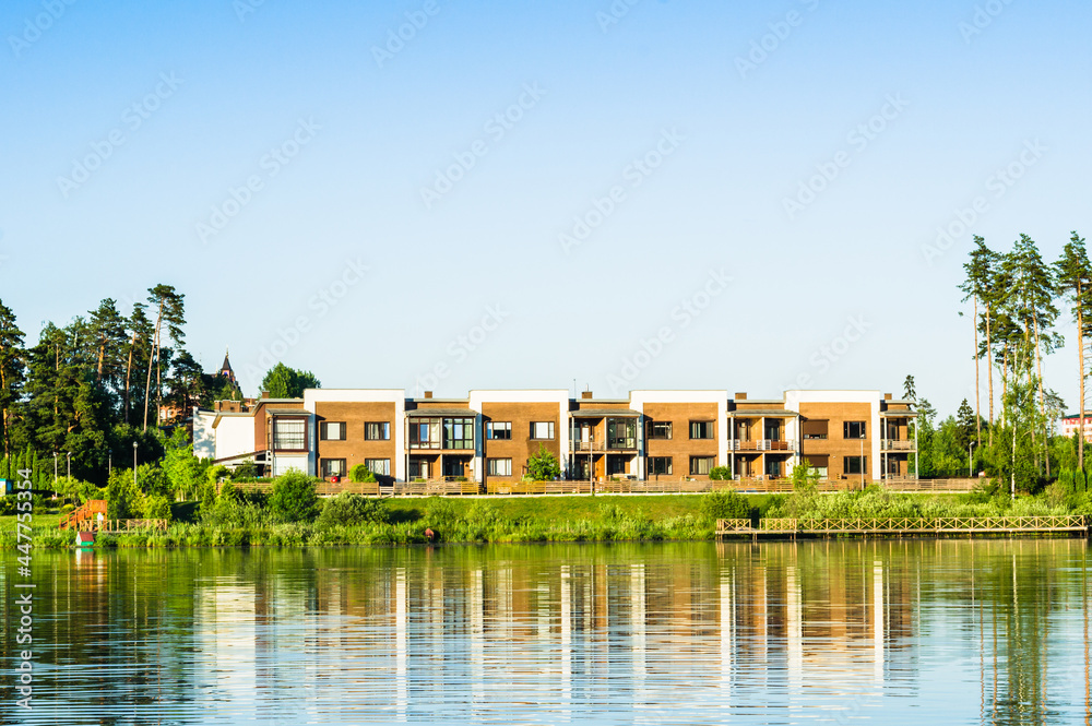 Modern urban housing near the pond shore. Contemporary residential architecture of suburban houses