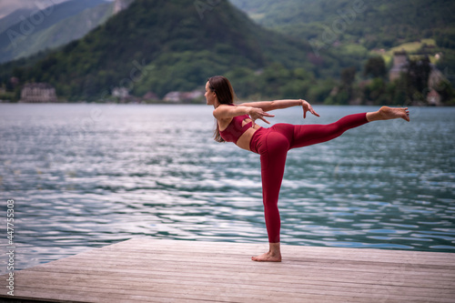 Flexible woman doing yoga in Warrior pose on quay photo