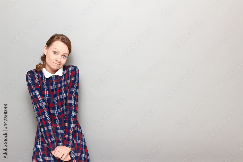 Portrait of funny confused young blond woman wearing checkered dress Portrait of funny confused young blond woman wearing checkered dress