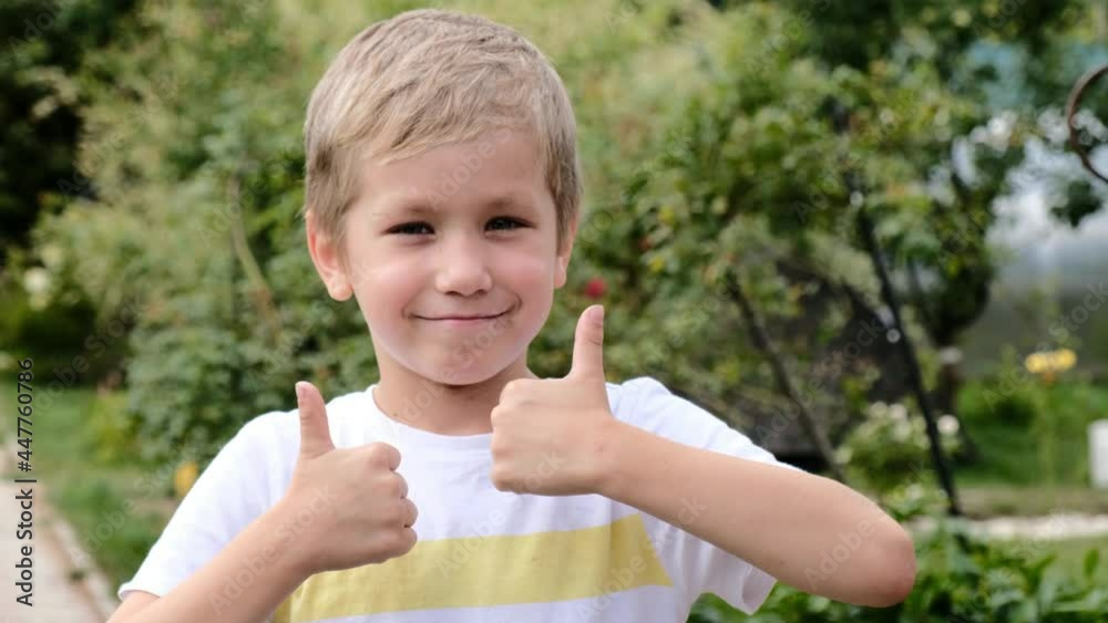 Happy cheerful cute boy 6 years old outside showing thumb up Happy cheerful cute boy 6 years old outside showing thumb up