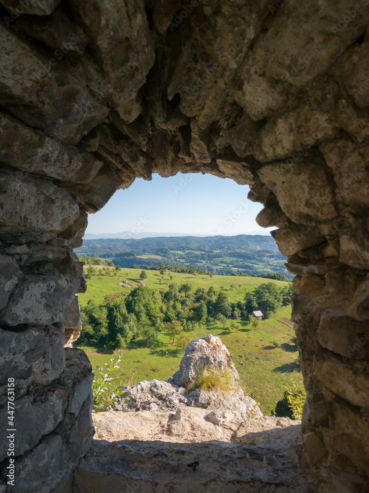 Panoramic hilly landscape of Srebrenik village with forests and meadows viewed through stone window of medieval ottoman fortress Srebrenik