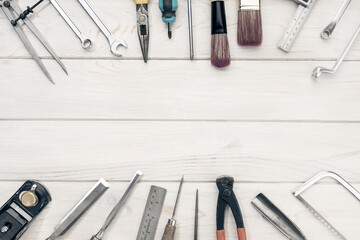 Border frame of work tools on white wooden table with copy space. Top view