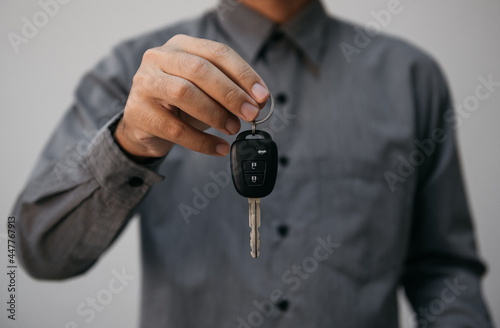 Close up hands holding car keys. man holding key of car giving to agent of Insurance for sell. business investment Insurance Car seizure and car concept.