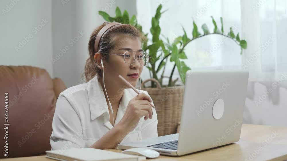 Young Asian woman look at laptop, greeting and talk to friends or family on video call online meeting at home. Remote internet conference, social distancing, new normal lifestyle 2021 concept. Young Asian woman look at laptop, greeting and talk to friends or family on video call online meeting at home. Remote internet conference, social distancing, new normal lifestyle 2021 concept.