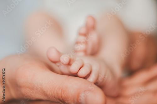 Soft focus close-up of newborn baby feet. Hands of a father holding baby feet.