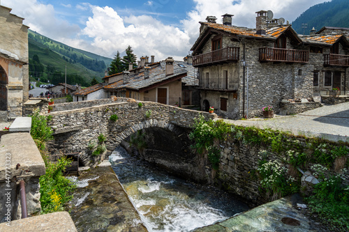 The Varaita river passing under old stone bridge in the village of Chianale, Varaita Valley, Piedmont, Italy photo