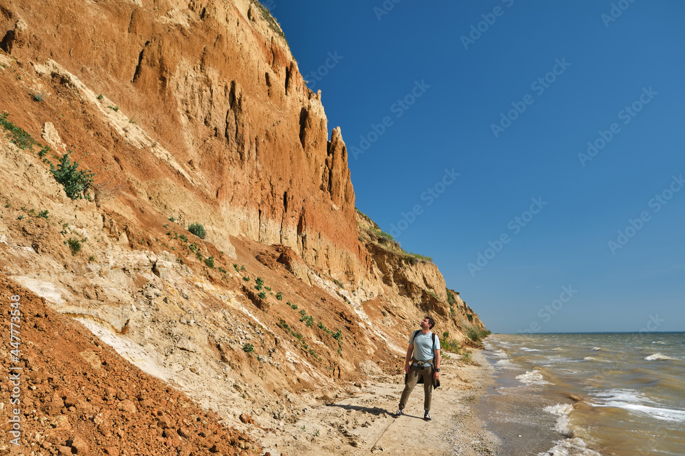 young man and backpack walks alone along a sand hill