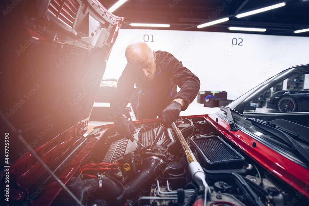 Naklejka premium Man repairing car engine with his tools. Car service
