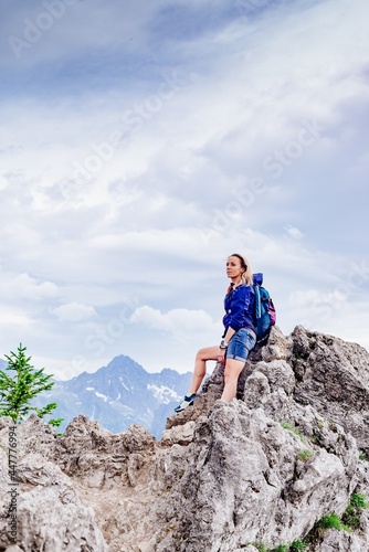 Woman traveler standing on a rock in the mountains. He admires the beautiful mountain views.