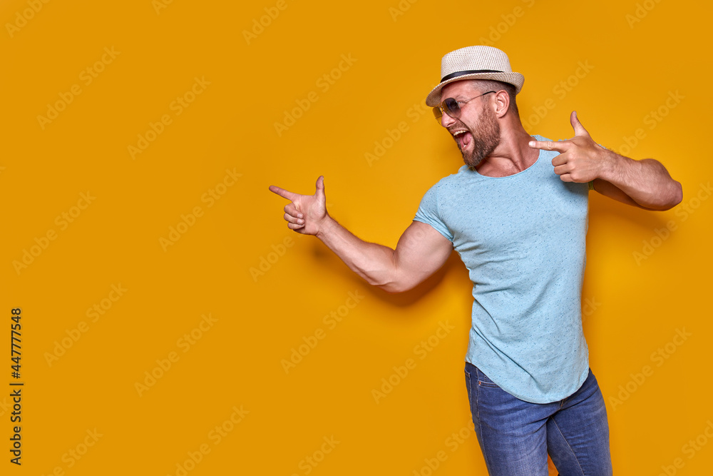 Young man on vacation wearing shirt and summer hat over yellow background pointing finger with successful idea. 