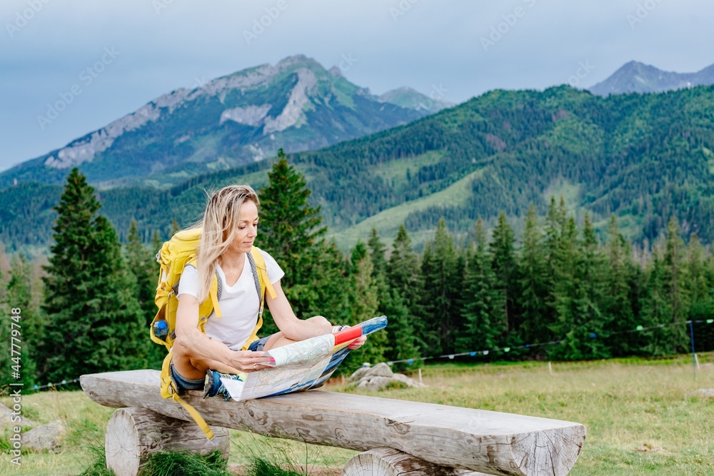 Girl traveler with yellow backpack sitting on a bench with a paper map. Girl traveler with yellow backpack sitting on a bench with a paper map.