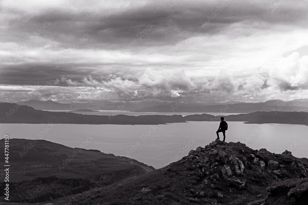 Ein Bergsteiger steht auf einem Gipfel hoch über einem großen See