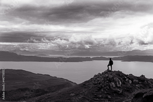 Ein Bergsteiger steht auf einem Gipfel hoch über einem großen See © Astrid Gast