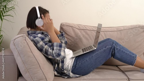 Young beautiful woman is trained online lying at home on the couch. The concept of working online and freelancing.