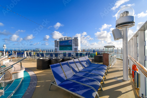 An empty cruise ship upper deck on an unidentifiable large cruise ship liner on the sea as the sun sets over the ocean.