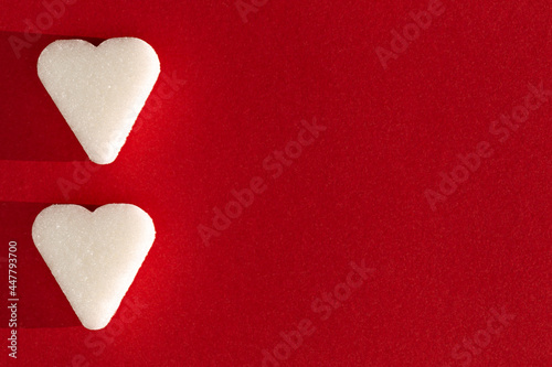 Two Sugar cubes, heart form on a red background with deep shadow. Love concept macro