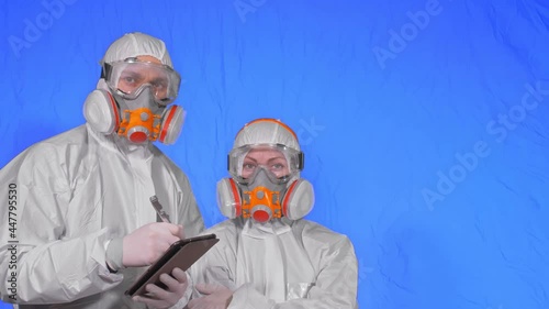 Scientist virologist in respirator makes write in an tablet computer with stylus. Man and woman wearing protective medical mask. Health safety virus coronavirus epidemic 2019 nCoV. Chroma key blue. photo