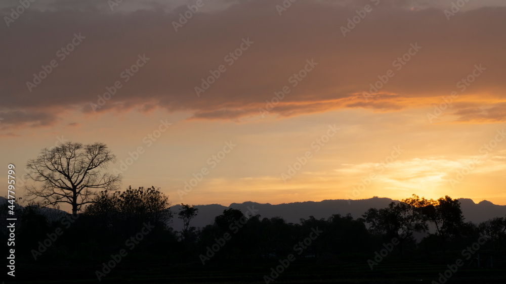 The sunset behind the hill, looks warm and calm with a rural atmosphere