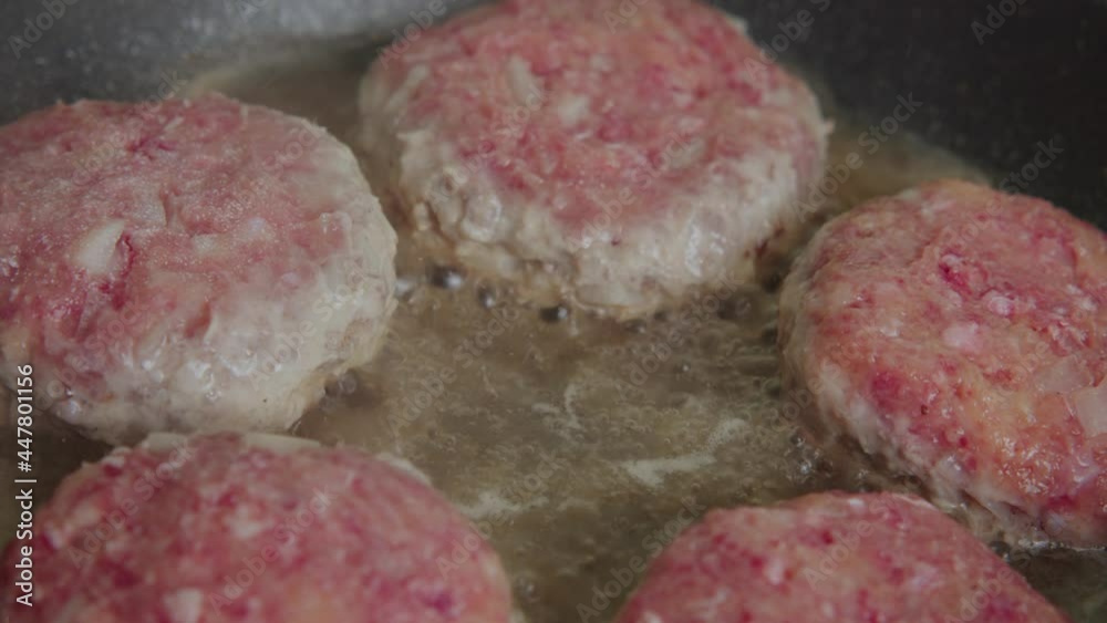 We cook juicy beef and pork cutlets for a burger for breakfast. The meat is fried in the kitchen in a sward. Slow motion.