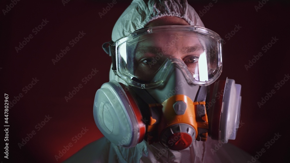 Man in protective costume suit, gas protect medical antibacterial antiviral spray paint mask. Doctor health worker in respirator. Concept health virus coronavirus epidemic. Radiation Nuclear war.