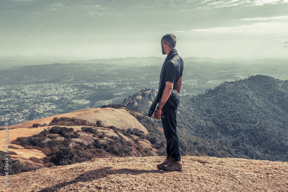 Homem negro pensativo olhando o horizonte do alto da montanha