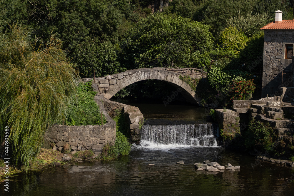 Old medieval stone bridge with waterfall and willow tree in rural Portugal. Close up. Old medieval stone bridge with waterfall and willow tree in rural Portugal. Close up.