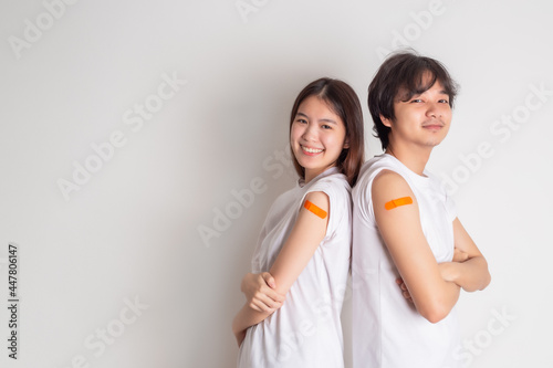 Fotografi Young Asian couple showing thumb up gesture and shows off an orange bandage after receiving the covid-19 vaccine