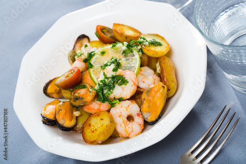 Tasty stewed potato served on plate with seafood - shrimps and mussels