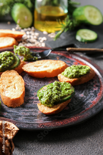 Tasty toasts with pesto sauce on dark background, closeup