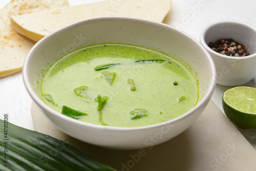 Bowl of tasty green curry on light background, closeup