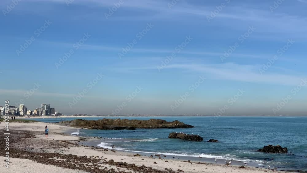 People walking on Big Bay rocky beach with views of Bloubergstrand beach People walking on Big Bay rocky beach with views of Bloubergstrand beach