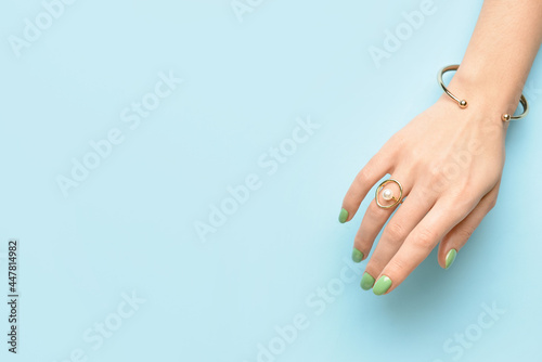 Female hand with beautiful manicure and jewelry on color background