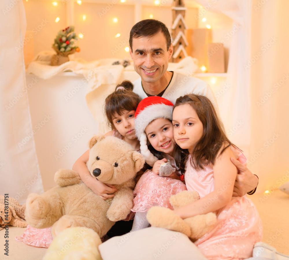 family portrait of a father and children in home interior decorated with lights family portrait of a father and children in home interior decorated with lights