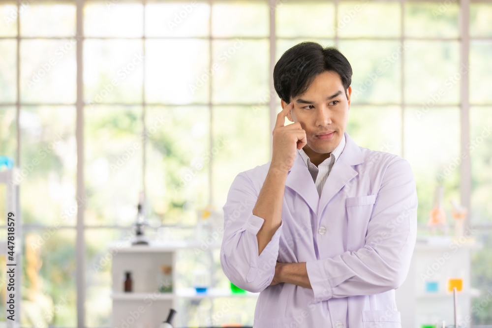 Asian man scientist or researcher standing wearing white coat and serious face thinking about question, very confused idea in laboratory. Concept thinking for medical. Asian man scientist or researcher standing wearing white coat and serious face thinking about question, very confused idea in laboratory. Concept thinking for medical.